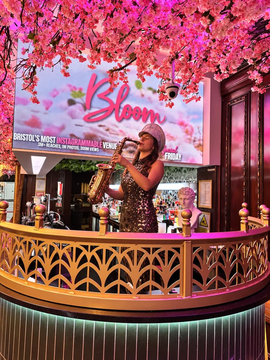 Live sax player performing on the balcony under the Bloom sign at Bloom cocktail bar, Park Street, Bristol